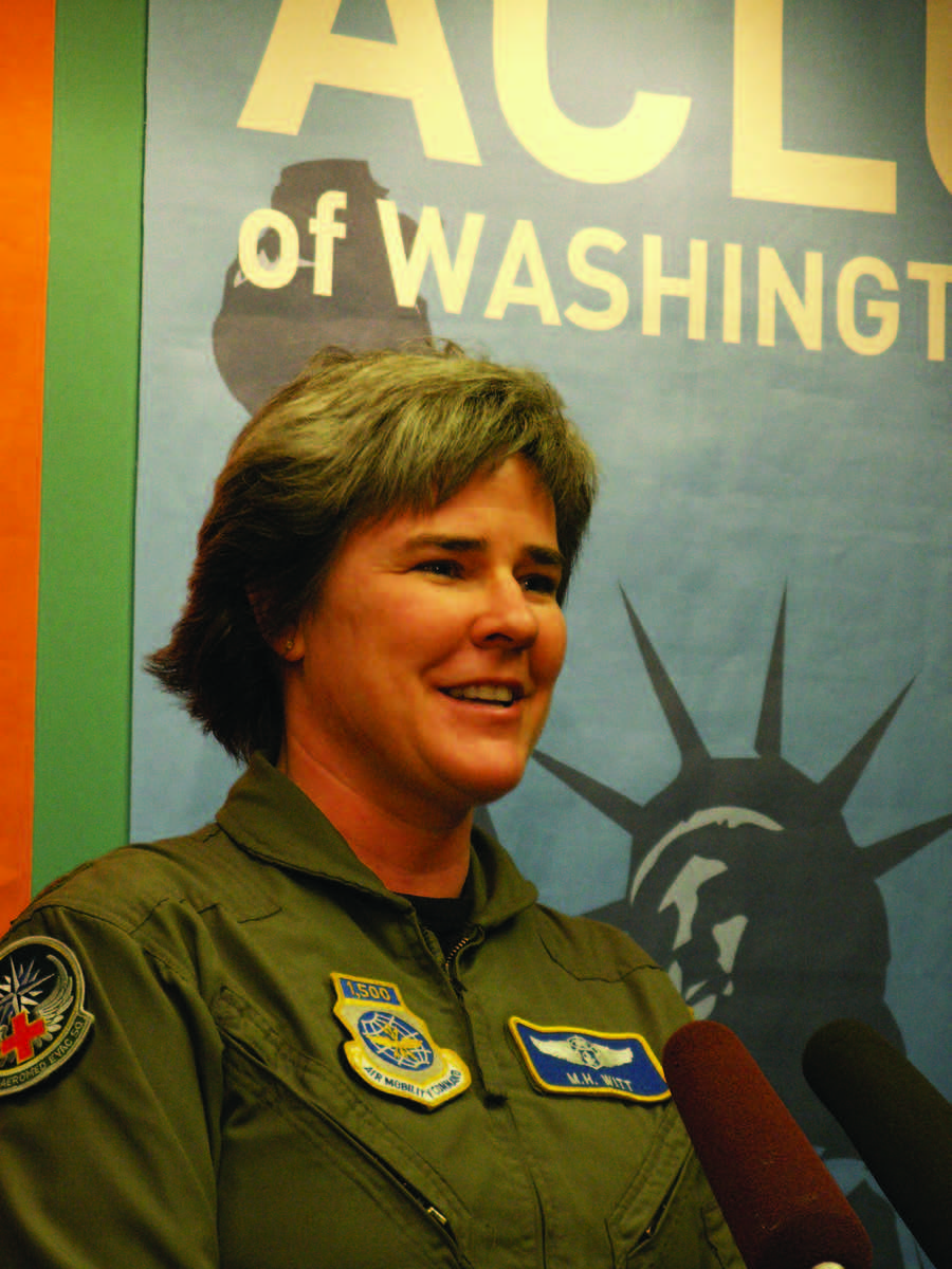 A photograph of Margaret Witt in uniform, standing in from of an Ƶ of Washington sign