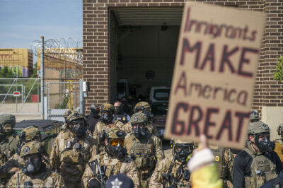 Heavily armed ICE and Border Patrol agents guard the Broadview ICE facility from peaceful protesters opposed to 'Operation Midway Blitz' in Chicagoland; their sign reads 'Immigrants Make America Great'