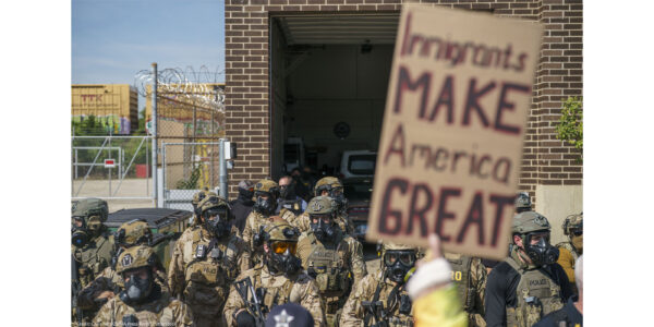 Heavily armed ICE and Border Patrol agents guard the Broadview ICE facility from peaceful protesters opposed to 'Operation Midway Blitz' in Chicagoland; their sign reads 'Immigrants Make America Great'