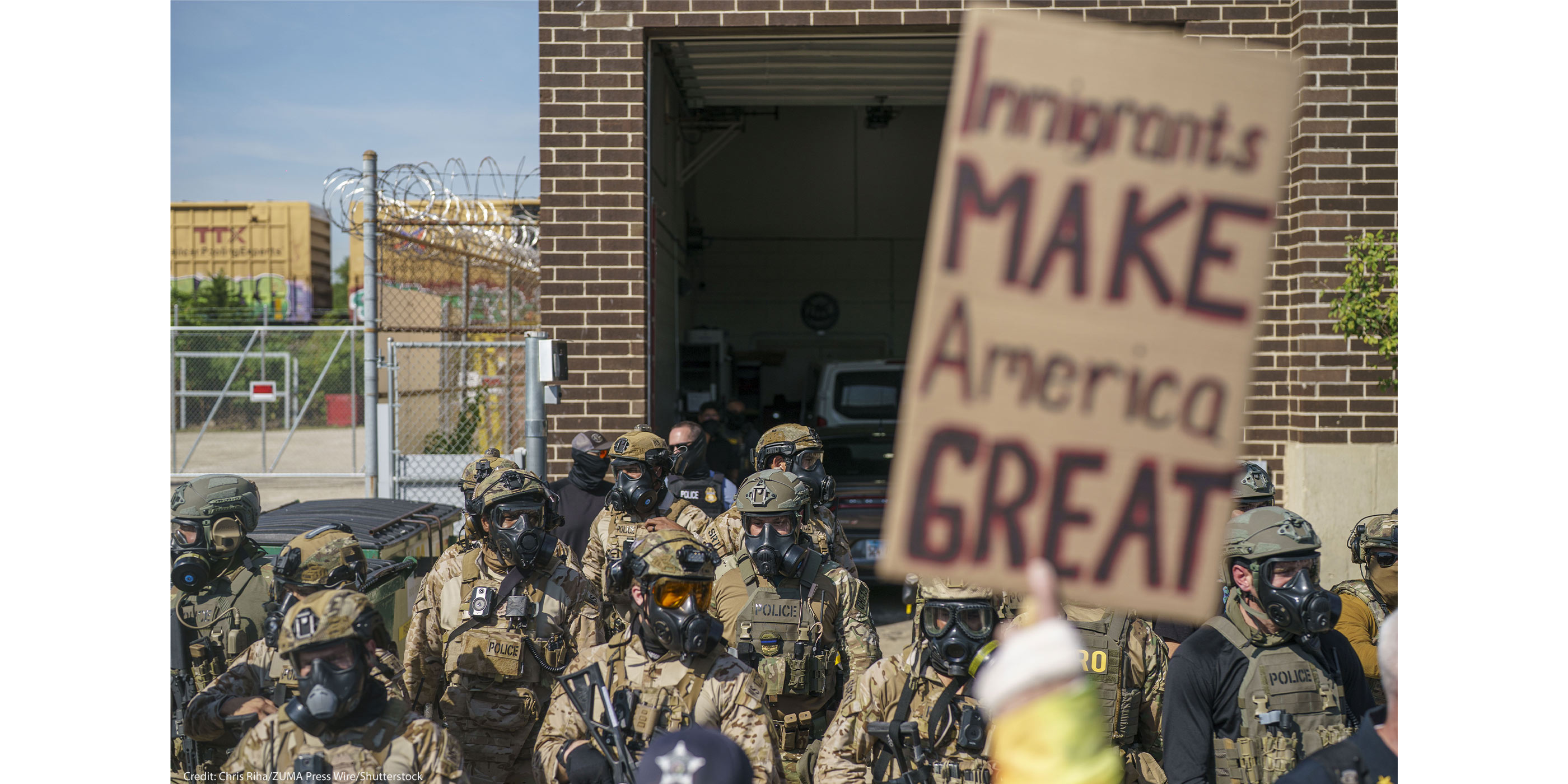 Heavily armed ICE and Border Patrol agents guard the Broadview ICE facility from peaceful protesters opposed to 'Operation Midway Blitz' in Chicagoland; their sign reads 'Immigrants Make America Great'