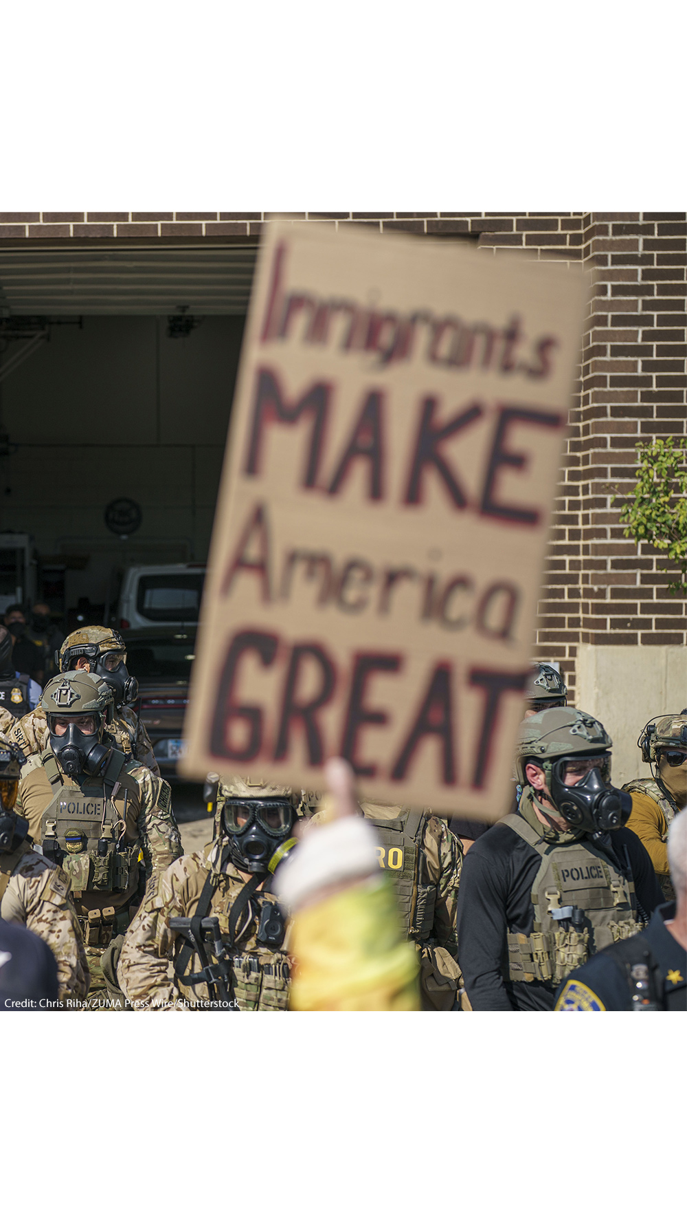 Heavily armed ICE and Border Patrol agents guard the Broadview ICE facility from peaceful protesters opposed to 'Operation Midway Blitz' in Chicagoland; their sign reads 'Immigrants Make America Great'