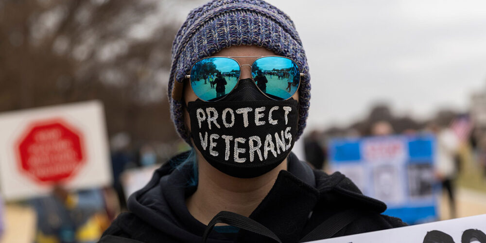 A demonstrator wears a mask with the text ''Protect Veterans'' during the ''Veterans March'' at the National Mall in Washington.