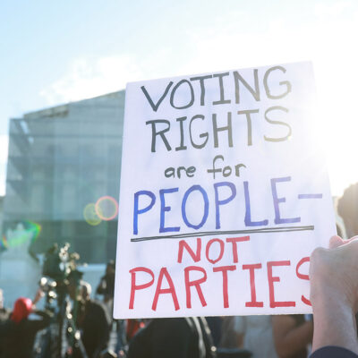 An individuals holding a sign saying "Voting Rights Are For People Not Parties," outside of the U.S. Supreme Court ahead of arguments in the Voting Rights case Callais v. Landry.