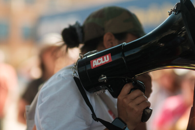 A demonstrator holding a megaphone with an ACLU sticker.