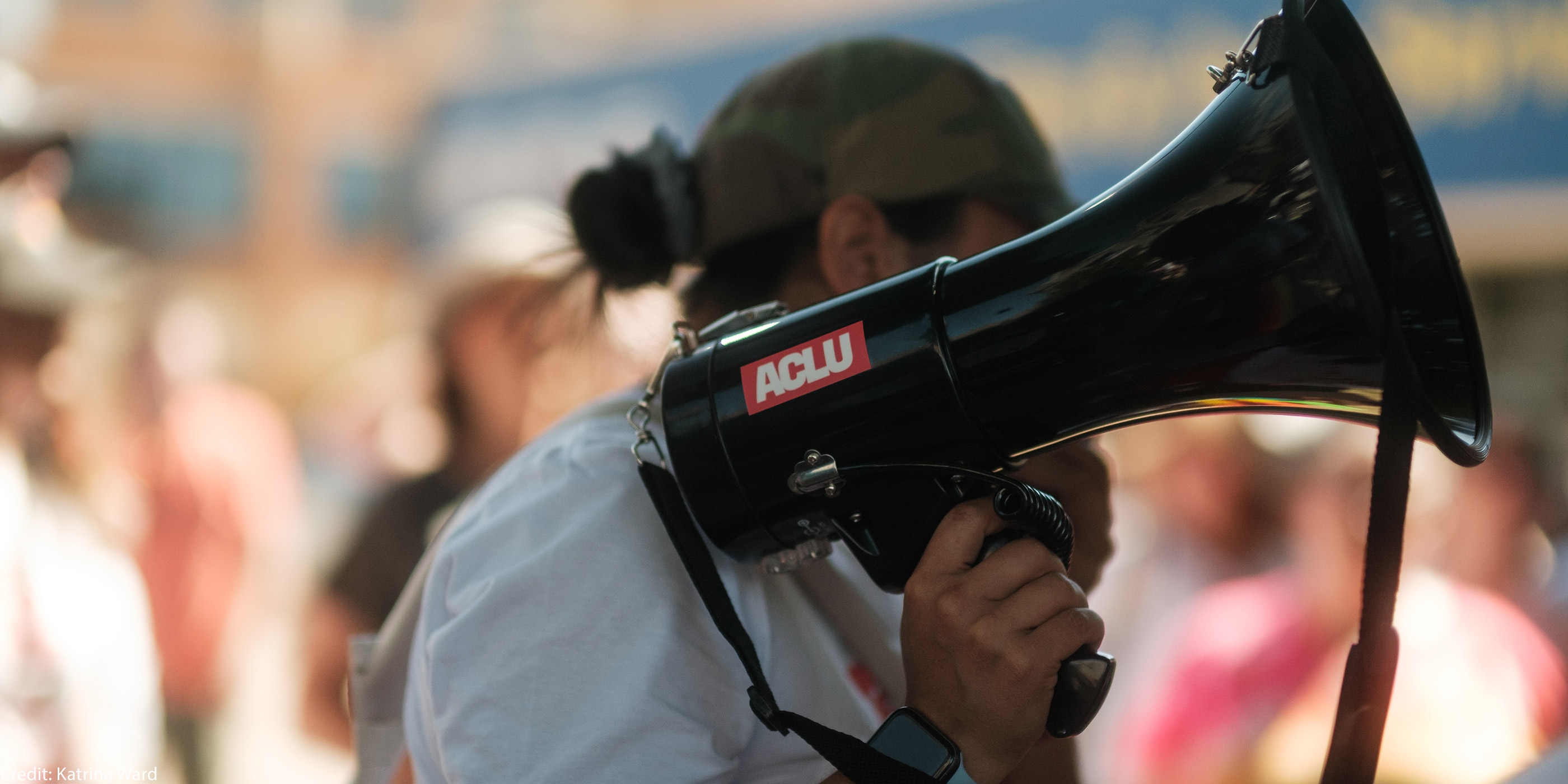 A demonstrator holding a megaphone with an ACLU sticker.