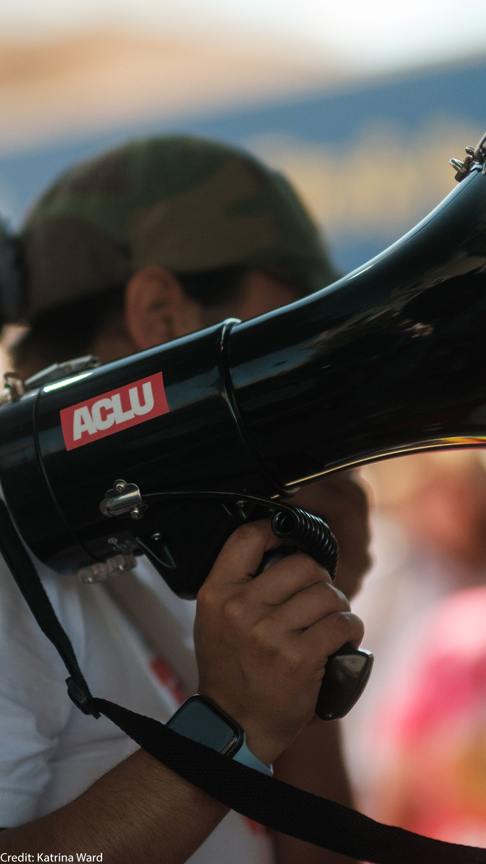 A demonstrator holding a megaphone with an ACLU sticker.