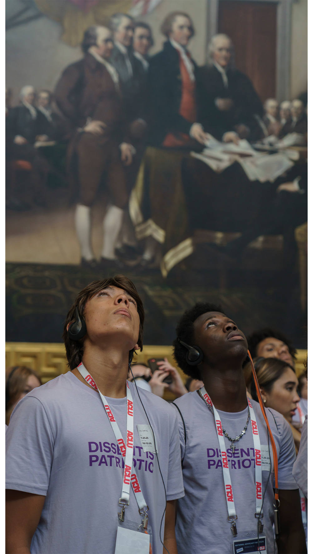 With a large painting of the Founding Fathers signing the Declaration of Independence in the background, two students in the ACLU’s National Advocacy Institute wearing “Dissent Is Patriotic” ACLU shirts and audio tour headsets look upward inside the U.S. Capitol Building,