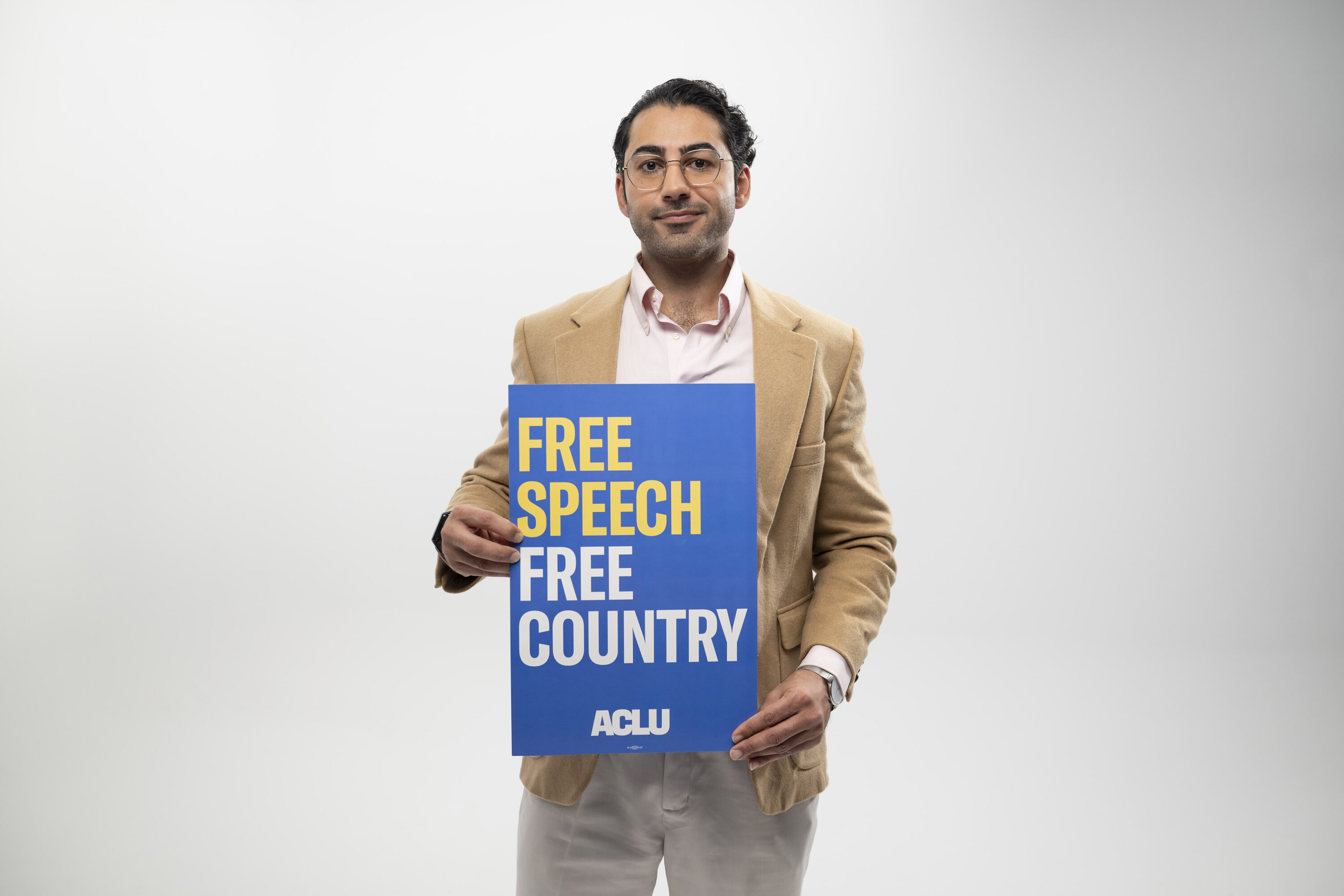 Mohsen Mahdawi holds a sign that reads Free Speech Free Country