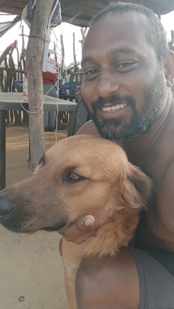 Man kneeling outside hugging dog