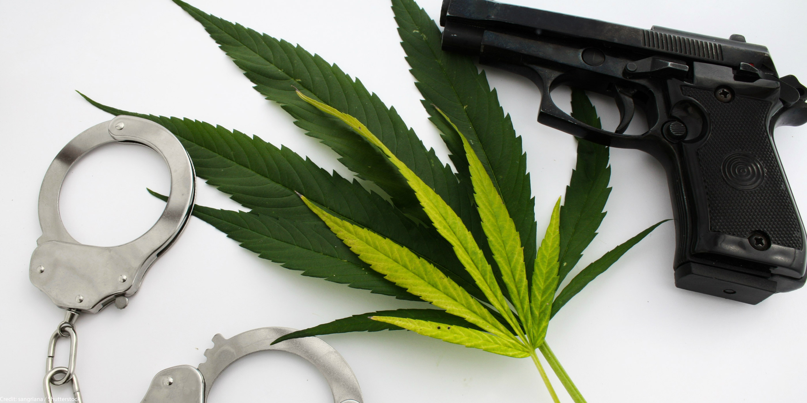 Handcuffs and a handgun next to cannabis leaves on a white background.