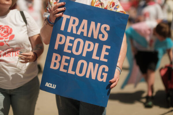 A protestor holds a sign that says Trans People Belong.