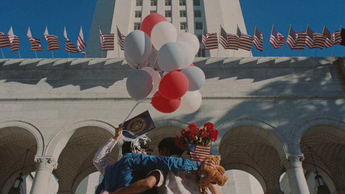 A family celebrate citizenship in front of Los Angeles City Hall with red, white, and blue balloons.