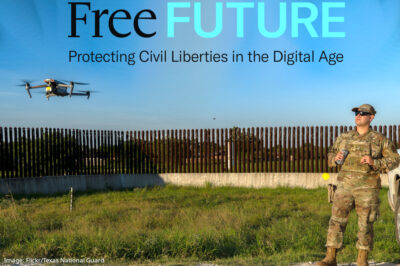 A drone hovering low as a man in camouflage military clothing watches