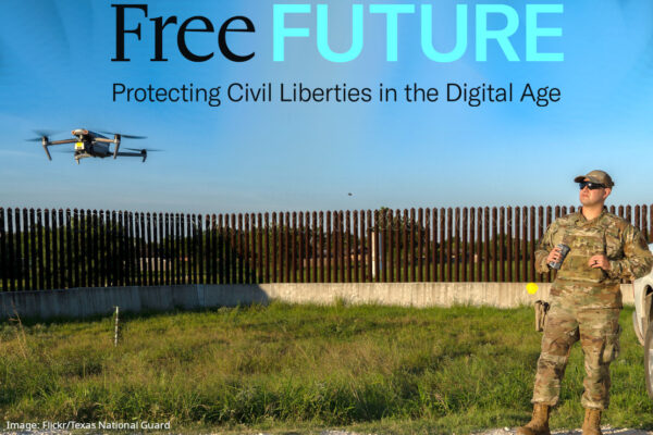 A drone hovering low as a man in camouflage military clothing watches