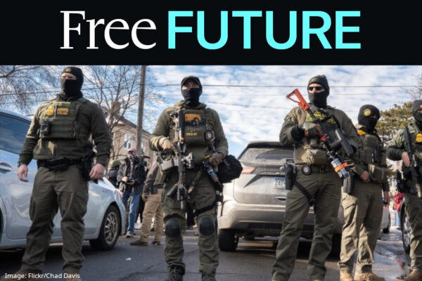 Immigration agents dressed up as soldiers with big guns facing the camera with cars and sky behind them