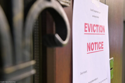 A notice of eviction of tenants hanging on the door of a house.