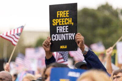 A protestor holds a sign that says Free Speech, Free Country