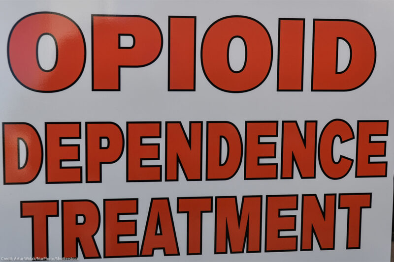 Close-up of a sign reading “OPIOID DEPENDENCE TREATMENT” in large red letters on a white background.