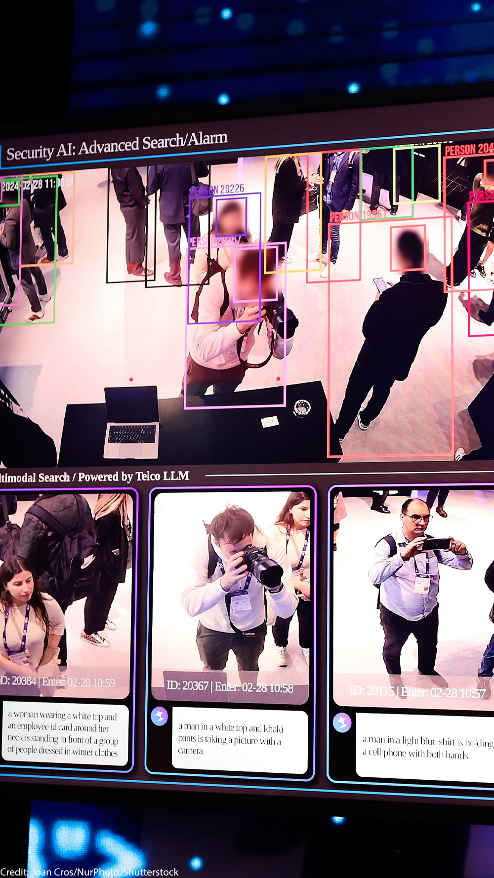 Large display showing an AI security surveillance dashboard using facial recognition-style tracking, with colored boxes around people in CCTV footage and labeled panels for "Advanced Search/Alarm," "Anomaly Analytics" (fire/smoke, violent situation, fall detection), and "Privacy Anonymization."