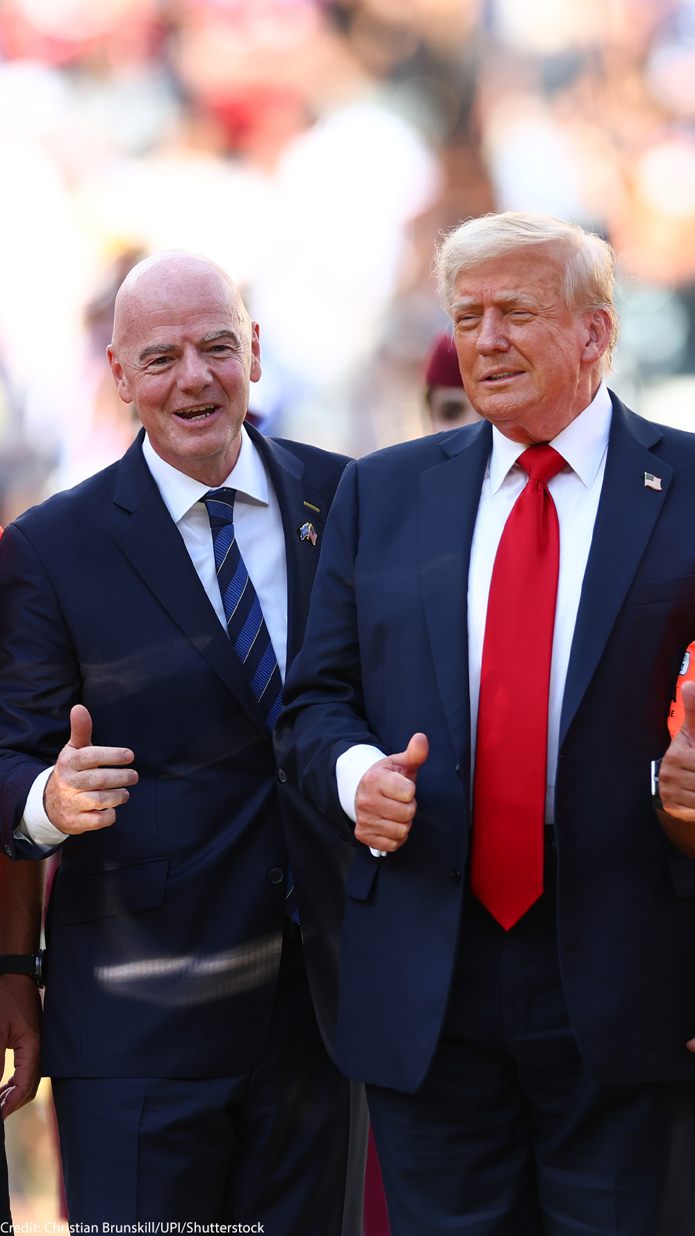 FIFA President Gianni Infantino and President Donald Trump pose with FIFA officials in bright orange referee jerseys and medals during the awards ceremony after Chelsea defeated Paris Saint-Germain 3–0 in the 2025 FIFA Club World Cup final at MetLife Stadium in East Rutherford, New Jersey.