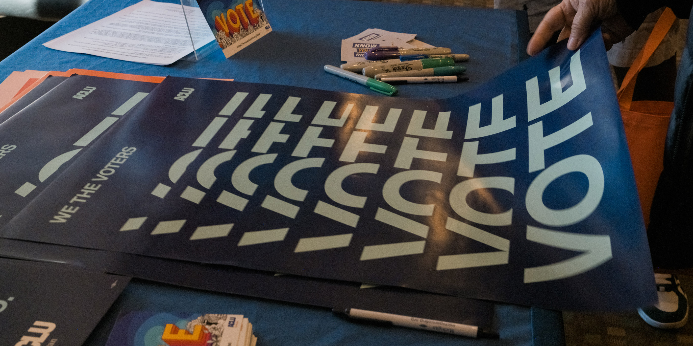 A stack of poster from the ACLU of Michigan urging individuals to vote.