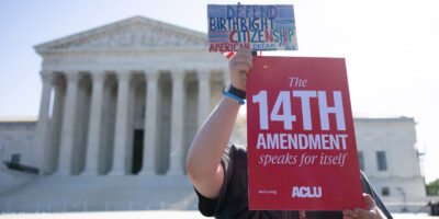 A demonstrator holding signs advocating for the 14th Amendment at the U.S. Supreme Court in Washington, D.C. for the birthright citizenship case Trump v. Barbara