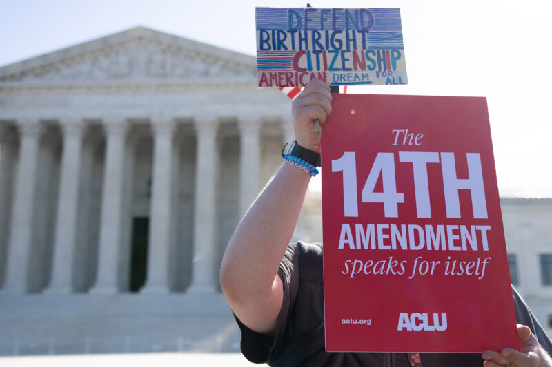 A demonstrator holding signs advocating for the 14th Amendment at the U.S. Supreme Court in Washington, D.C. for the birthright citizenship case Trump v. Barbara