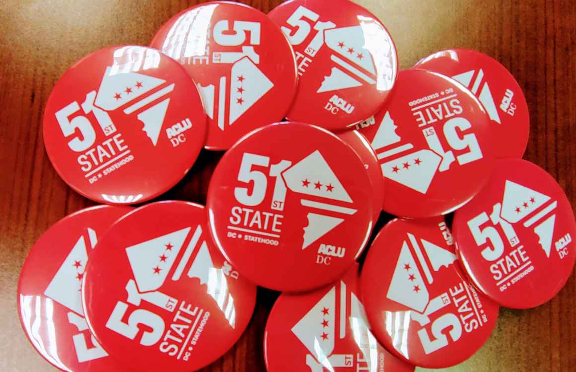 Photo of a pile of red pins that read "51st State"