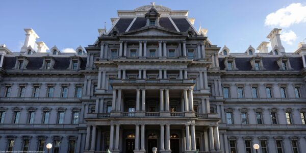 Front view of the Eisenhower Executive Office Building, which houses the U.S. Office of Management and Budget, showing the historic government building's rows of windows, ornate columns, and central staircase under a clear blue sky.