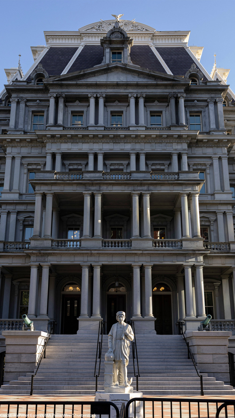 Front view of the Eisenhower Executive Office Building, which houses the U.S. Office of Management and Budget, showing the historic government building's rows of windows, ornate columns, and central staircase under a clear blue sky.
