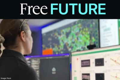 A police officer looking at data screens at front of a dark command center