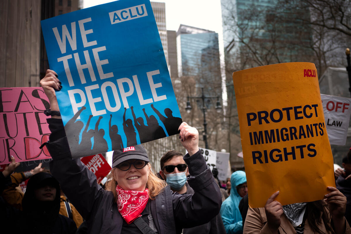 A crowd of people hold protest signs and rally in New York City