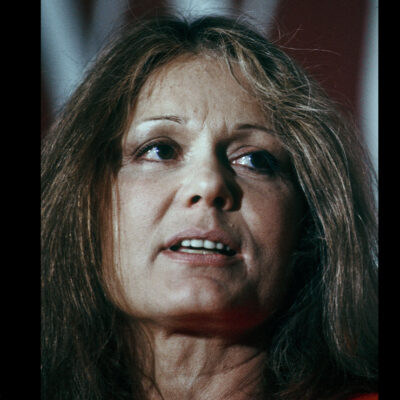 A headshot of Gloria Steinem on a black background.