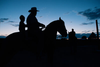 The silhouette of a man and a child on a horse.
