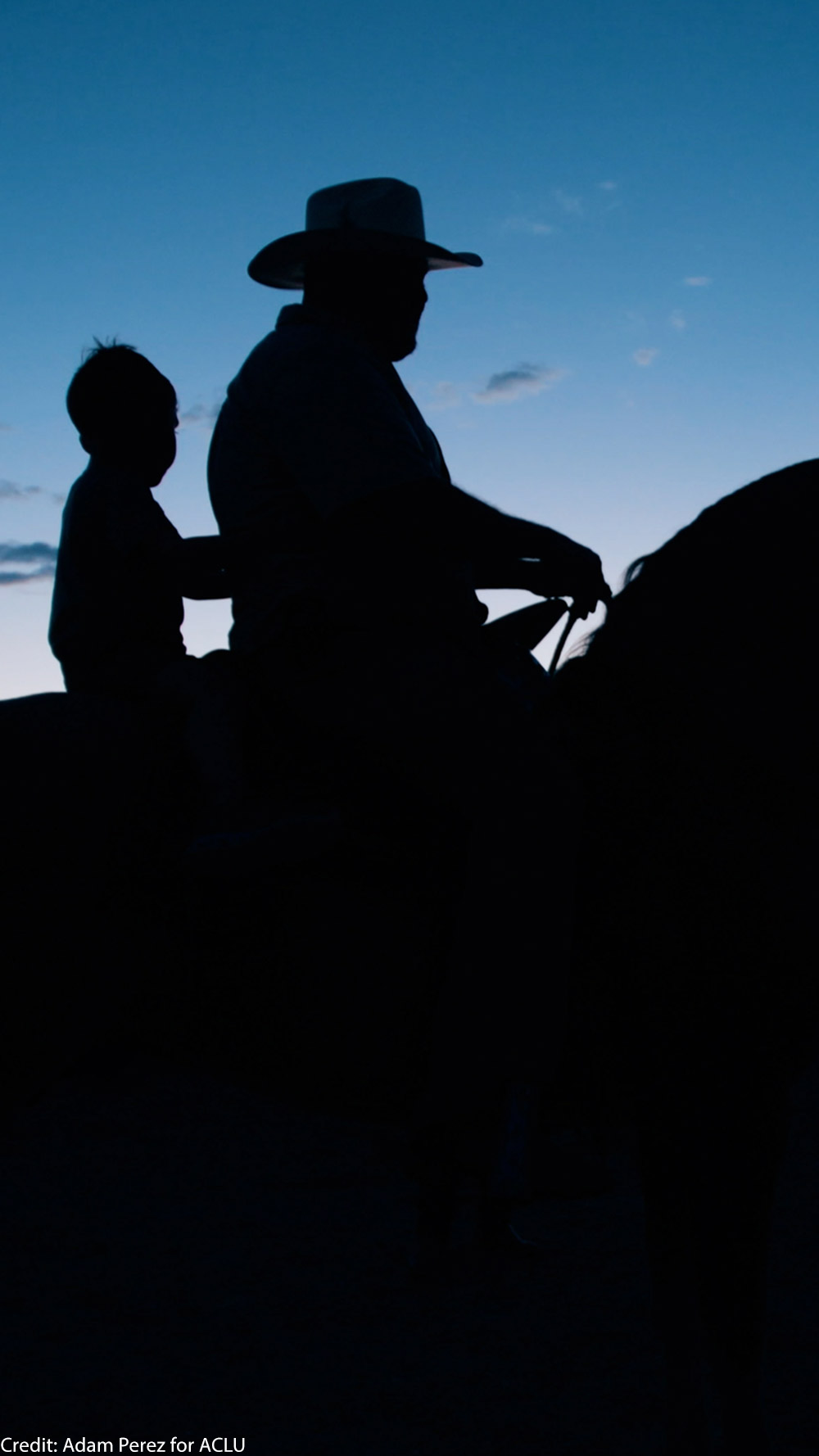 The silhouette of a man and a child on a horse.
